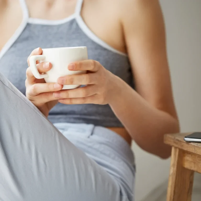 A woman sitting inside her home and relaxing, holding bowl of soup post surgery.